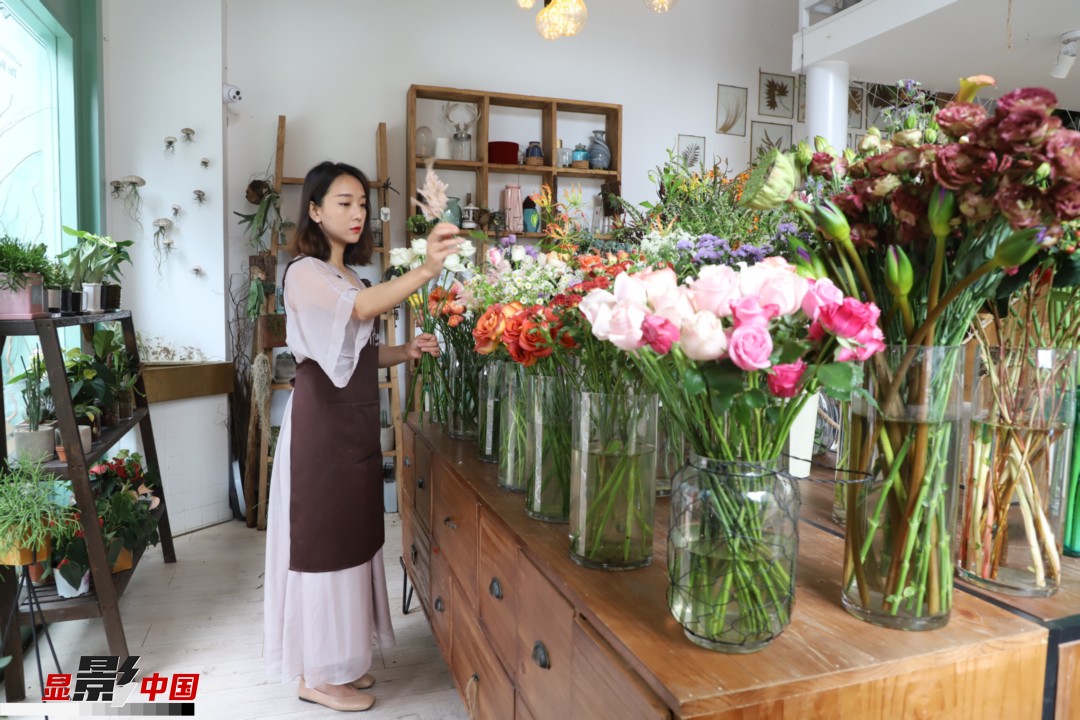 王黎媛是一名河南姑娘，在昆明念完大學(xué)后，就再也舍不下春城的藍(lán)天陽光、青山碧水，更舍不下這里的四時繁花，于是就干脆留了下來，成了一名媒體人。2017年的時候又毅然辭去工作，創(chuàng)業(yè)開起了花店，成了都市里的一名“花房姑娘”。圖為王黎媛在自己的花店中整理鮮花。新華網(wǎng) 周亞平/攝 念新洪/文